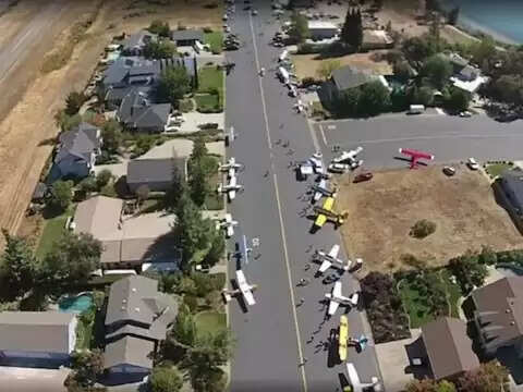 आजकल हर किसी के घर में कार या बाइक होती है। उसे जहां जाना होता है, वह गाड़ी निकाल कर चल देता है। आज हम आपको जिस गांव के बारे में बताने जा रहे हैं, वहां लोगों के पास कार नहीं है, उनके पास सीधा हवाई जहाज है। यह उनके लिए उतना ही सामान्य है जितना कि हमारे लिए वाहन। ऑफिस जाने से लेकर परिवार के साथ डिनर करने तक ये लोग हवाई जहाज का इस्तेमाल करते हैं.  सुनने में शायद आपको अजीब लगे लेकिन अमेरिका के कैलिफोर्निया में एक गांव ऐसा है जहां हर किसी के घर के सामने एक हवाई जहाज खड़ा है। एक हवाई जहाज़ सीधे वहाँ जाता है जहाँ वे जाना चाहते हैं, जैसे कार। यह गांव तब सुर्खियों में आया जब इससे जुड़े वीडियो सोशल मीडिया पर वायरल हुए। यहां के लड़कों की चौड़ाई आपको रनवे जैसा महसूस कराएगी।  हवाई जहाजों को कारों की तरह पार्क किया जाता है कैलिफोर्निया में कैमरून एयर पार्क नाम की यह जगह आम गांवों से अलग है। यहां चौड़ी सड़कें बनाई गई हैं ताकि एयरपोर्ट तक पहुंचने के लिए रनवे के तौर पर इनका इस्तेमाल किया जा सके। इस गांव के हर घर के बाहर गैरेज जैसा हैंगर होता है, जहां वे अपने विमान खड़े करते हैं। लोग जहां भी जाना चाहते हैं, हवाई जहाज से जाते हैं। दिलचस्प बात यह है कि यहां रहने वाले ज्यादातर लोग पायलट हैं और अपना विमान खुद उड़ाते हैं। यह समुदाय में एक तरह की मक्खी है, जहां लोग शनिवार की सुबह एक साथ मिलते हैं और एक साथ स्थानीय हवाई अड्डे के लिए उड़ान भरते हैं।   अमेरिका में सैकड़ों एयर पार्क हैं एक अनुमान के मुताबिक अमेरिका में 610 ऐसे एयर पार्क हैं, जहां हर घर में एक प्लेन है। द्वितीय विश्व युद्ध के दौरान बनाए गए हवाई क्षेत्रों को परिवर्तित नहीं किया गया था और उन्हें आवासीय हवाई पार्कों में बनाया गया था। सेवानिवृत्त सैन्य पायलट यहां रहते हैं। 1946 के दौरान अमेरिका में कुल 400,000 पायलट थे जो इन हवाई पार्कों में रहने लगे थे। कैमरून पार्क 1963 में बनाया गया था और इसमें कुल 124 घर हैं। यहां की सड़कों के नाम भी एयरक्राफ्ट के नाम पर रखे गए हैं और रोड साइन्स को भी एयरक्राफ्ट फ्रेंडली बनाया गया है।